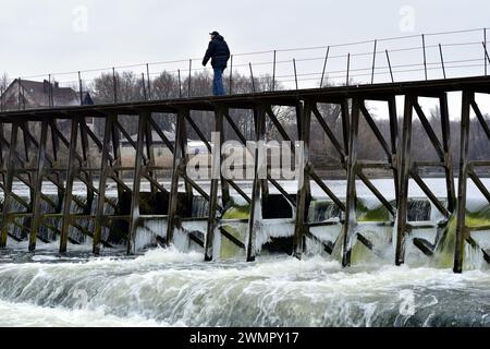 Barrage sur la rivière. Un homme marche le long du sommet. L'eau qui roule bout par le haut. Banque D'Images