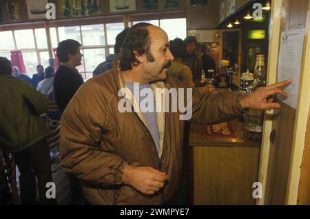 Klondyker Eastern Europen Trawlerman lisant un avis en russe sur le concert du quatuor à cordes d'Édimbourg qui sera joué sur le Loch Broom. Le bar du Seaforth Hotel. Ullapool, Écosse 1986 Royaume-Uni HOMER SYKES Banque D'Images