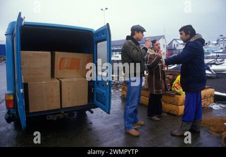 Klondykers – pêcheurs d’Europe de l’est – en congé de terre, ils travaillent sur des bateaux de pêche d’usine sur le Loch Broom, Ullapool. Les deux hommes à droite sont des pêcheurs négociant avec un local – Dellboy – qui possède une camionnette pleine de radiateurs et d’autres appareils électriques qu’il espère vendre. Les chalutiers étaient très désireux d'acheter des produits électriques pour les ramener chez eux. Ullapool, Écosse années 1986 1980 Royaume-Uni HOMER SYKES Banque D'Images