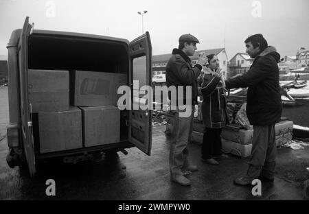 Klondykers – pêcheurs d’Europe de l’est – en congé de terre, ils travaillent sur des bateaux de pêche d’usine sur le Loch Broom, Ullapool. Les deux hommes à droite sont des pêcheurs négociant avec un local – Dellboy – qui possède une camionnette pleine de radiateurs et d’autres appareils électriques qu’il espère vendre. Les chalutiers étaient très désireux d'acheter des produits électriques pour les ramener chez eux. Ullapool, Écosse années 1986 1980 Royaume-Uni HOMER SYKES Banque D'Images
