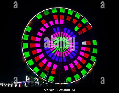 Mouvement intentionnel de la caméra, obturateur lent flou image de grande roue géante illuminée et tournant la nuit dans une foire amusante. Banque D'Images