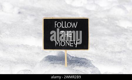 Suivez le symbole argent. Les mots conceptuels suivent l'argent sur un beau tableau noir de craie noire. Beau fond de neige blanc. Et suivez la Banque D'Images