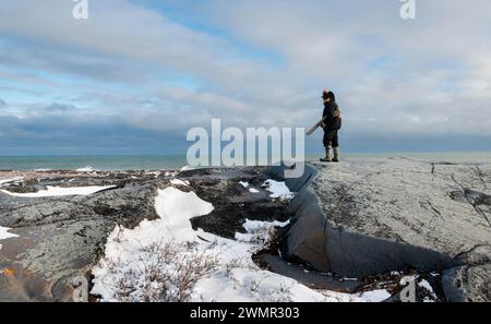 Un gardien armé surveille la côte de la baie d'Hudson à la recherche d'ours polaires au site historique Cape Merry à Churchill, au Manitoba, au Canada Banque D'Images