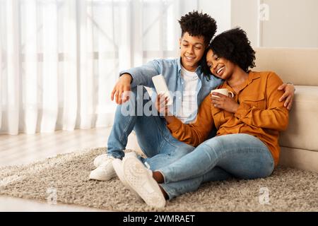 Un jeune couple confortable en tenue décontractée, confortablement relaxant sur un tapis en peluche Banque D'Images