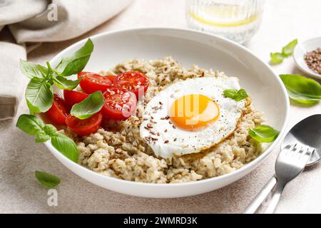 Flocons d'avoine avec oeuf frit côté soleil, tomates et basilic Banque D'Images