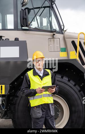 Homme travailleur avec tablette ordinateur se tient à côté du camion minier.. Banque D'Images