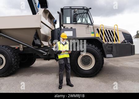 Homme travailleur avec tablette ordinateur se tient à côté du camion minier.. Banque D'Images