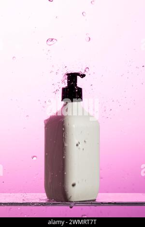 Une bouteille en plastique blanc avec une pompe noire est à flot dans un liquide rose Banque D'Images