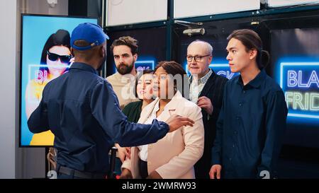 Groupe impatient de clients se battant avec l'employé du magasin de détail, poussant l'homme à entrer en premier dans le magasin de mode. Les acheteurs impatients en colère deviennent fous pendant les soldes du vendredi fou. Banque D'Images