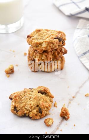 Flocons d'avoine faits maison, raisins secs, bouchées de biscuit aux pépites de chocolat en pile avec un verre de lait en composition verticale. Collation nutritive saine. Mise au point sélective o Banque D'Images