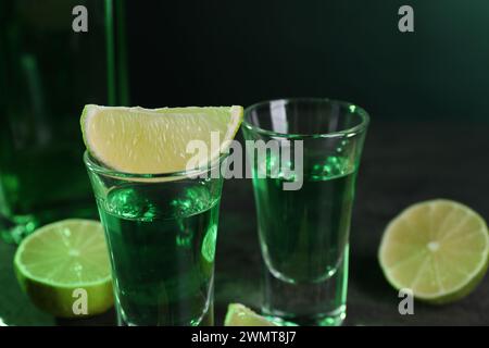 Absinthe dans des verres à dose et citron vert sur la table, gros plan. Boisson alcoolisée Banque D'Images