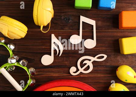 Concept de chanson de bébé. Notes en bois, tambourins et jouets sur table, pose à plat Banque D'Images