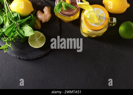 Pots Mason de limonade savoureuse à la menthe et au citron vert sur table noire Banque D'Images