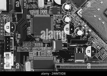 gros plan sur la carte de circuit imprimé avec des résistances, des condensateurs, des micropuces et des composants électroniques. b/w. Banque D'Images