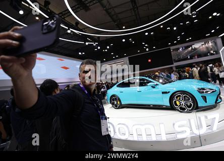 Pékin, Espagne. 26 février 2024. Un homme prend des selfies avec la voiture SU7 de Xiaomi lors du Mobile World Congress (MWC) à Barcelone, Espagne, le 26 février 2024. L'édition 2024 du MWC, le salon leader mondial de la technologie mobile et des industries connexes, a ouvert ses portes lundi à Barcelone, en Espagne. Cette année, le MWC compte environ 2 400 exposants et 1 100 conférenciers, dont près de 300 sociétés chinoises telles que China Mobile, China Telecom, Huawei, ZTE, Lenovo, Xiaomi et iFlytek. Crédit : Gao Jing/Xinhua/Alamy Live News Banque D'Images