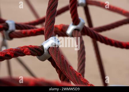 Sections de corde rouge attachées avec une pince métallique et un fond de sable brun Banque D'Images