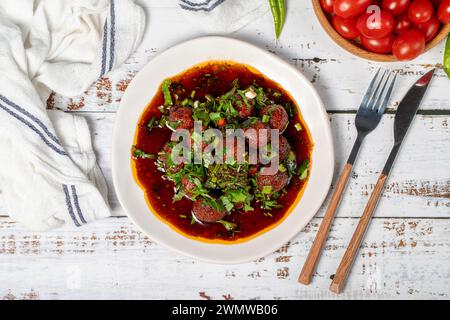 Boulettes de viande d'Alep. Saveurs asiatiques traditionnelles. Boulettes de viande avec pâte de tomate. Boulettes de viande d'Alep sur fond de bois blanc. Vue de dessus Banque D'Images