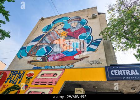 Une grande murale au bout d'un immeuble d'appartements, représentant des femmes traditionnelles et deux bébés, des enfants. À Almaty, Kazakhstan. Banque D'Images