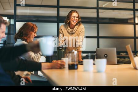 Divers professionnels participent à une discussion créative, mettant en valeur le travail d'équipe et la collaboration dans une salle de réunion de bureau animée. Dirigé par un leader confiant Banque D'Images