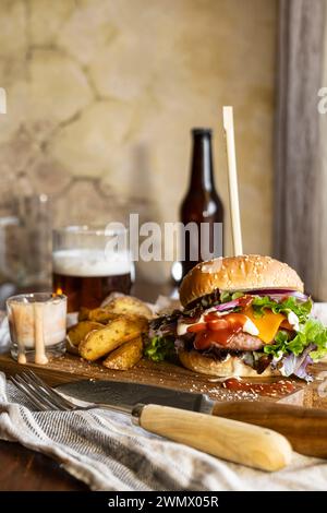 Hamburger appétissant sur une planche de bois, accompagné de frites croustillantes et de bière rafraîchissante, aspect délicieux et tentant, tir vertical Banque D'Images