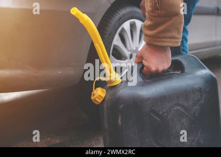 Un homme remplissant le réservoir de carburant de sa voiture avec du carburant diesel du jerry Can car il n'y a pas de carburant à la station-service, de près Banque D'Images