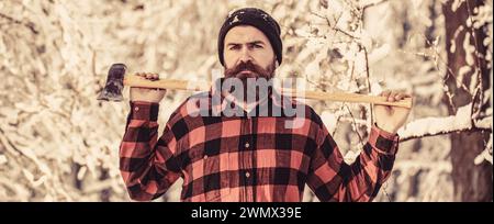 Concept de bûcheron. Homme de bûcheron travaillant dans la forêt d'hiver. Concept Hipster Woodsman. Homme dans le chapeau avec la barbe et la moustache tient hache. Bûcheron rentré Banque D'Images