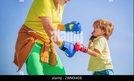 Combattant en bonne santé grand-père et petit-fils avec des gants de boxe. Petit garçon sportif à l'entraînement de boxe avec entraîneur. Homme de sport entraîneur de boxe petit garçon Banque D'Images