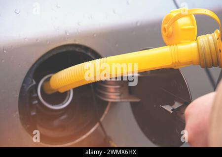 Un homme remplissant le réservoir de carburant de sa voiture avec du carburant diesel du jerry Can car il n'y a pas de carburant à la station-service, de près Banque D'Images