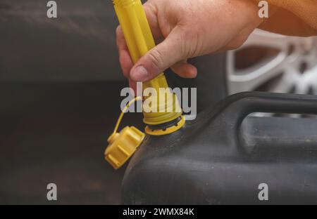 Un homme remplissant le réservoir de carburant de sa voiture avec du carburant diesel du jerry Can car il n'y a pas de carburant à la station-service, de près Banque D'Images