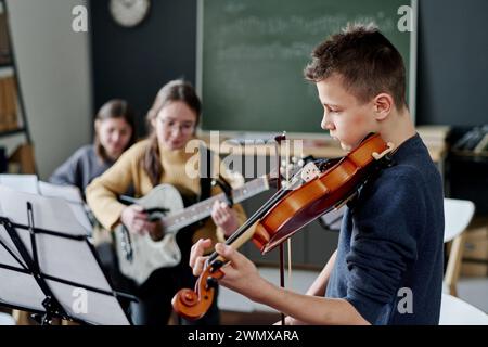 Plan sélectif d'un groupe de collège moderne pratiquant la musique dans la salle de classe, espace de copie Banque D'Images