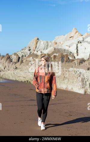 jolie femme blonde marchant joyeusement sur la plage Banque D'Images