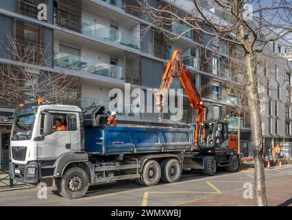 Gennevilliers, France - 02 02 2024 : travaux routiers en contre-jour. Travaux de développement du réseau de chauffage avec camion et grue de construction Banque D'Images