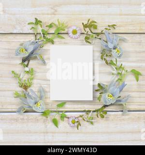 Printemps, couronne légère avec une feuille de papier vierge à remplir sur une table en bois. Pose à plat. Banque D'Images