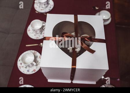 Une grande boîte festive contient un gâteau d'anniversaire sur une table décorée, entourée de cadeaux d'anniversaire. Célébrant une occasion joyeuse avec félicitations i Banque D'Images