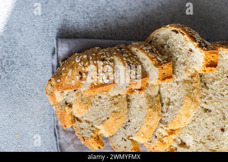 Du haut du pain au levain tranché surmonté d'une variété de graines sur un chiffon sur une surface grise Banque D'Images