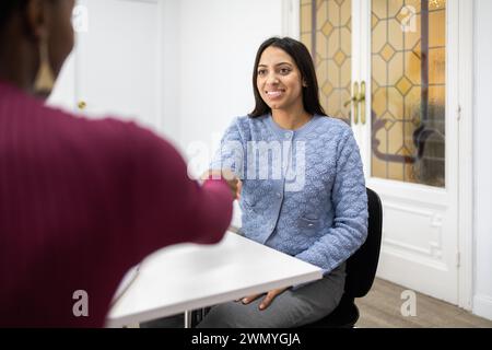 Une jeune femme professionnelle sourit avec confiance lors d'un entretien d'embauche, faisant une excellente première impression. Banque D'Images