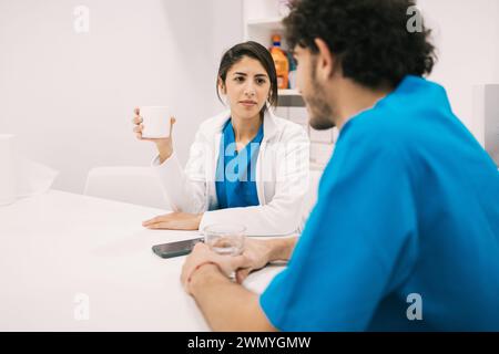 Une femme médecin discute avec un infirmier dans un cadre clinique moderne, possiblement avec des informations ou des consultations sur les soins aux patients. Banque D'Images