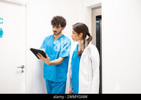 Deux professionnels de la santé discutent des soins prodigués aux patients en marchant dans un couloir hospitalier Banque D'Images