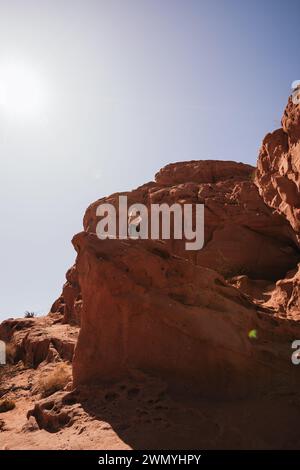 Une personne se tient au sommet d'une formation rocheuse rouge dans la région de Los Colorados sous un ciel bleu clair, mettant en valeur la beauté sauvage du deser du nord de l'Argentine Banque D'Images