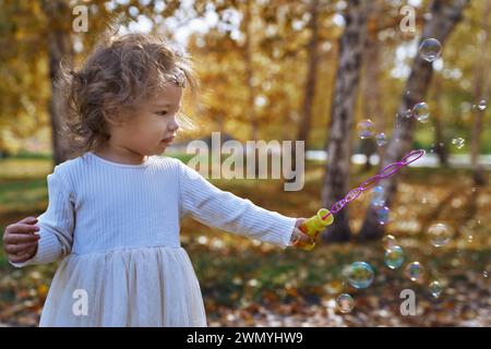 Un adorable tout-petit ethnique aime jouer avec des bulles un jour ensoleillé dans un parc, capturant l'essence de la joie innocente et du plaisir en plein air en Californie Banque D'Images