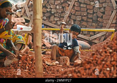 Dhaka, Bangladesh. 28 février 2024. Des hommes, des femmes et des enfants bangladais cassent des briques à Keranigonj briqueterie à Dhaka, au Bangladesh. Avec plus de la moitié de la population vivant en dessous du seuil de pauvreté, les femmes et les enfants sont souvent contraints à des travaux manuels pénibles tels que le bris de briques. Travaillant pieds nus et avec des ustensiles rugueux, chaque travailleuse gagne moins de 4 dollars US (320 Taka) et chaque enfant travailleur gagne moins de 2 dollars US par jour. (Crédit image : © Harun-or-Rashid/ZUMA Press Wire) USAGE ÉDITORIAL SEULEMENT! Non destiné à UN USAGE commercial ! Banque D'Images