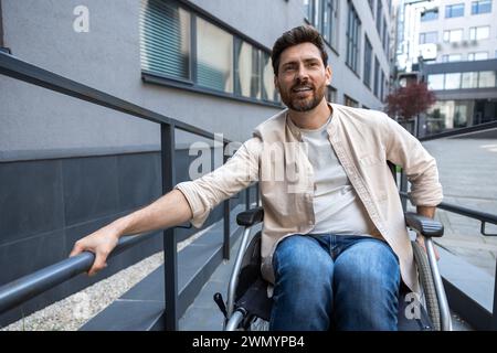 Jeune homme barbu aux cheveux foncés sur un fauteuil roulant Banque D'Images