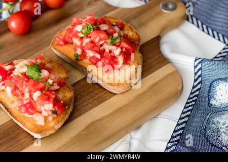 Bruschetta avec du pain rustique, tomates cerises, persil et oignon avec de l'huile d'olive sur la planche de bois. Banque D'Images