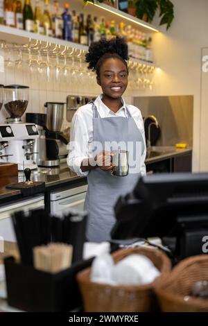 Souriante femme multiculturelle barista faisant du café debout au comptoir dans le café Banque D'Images