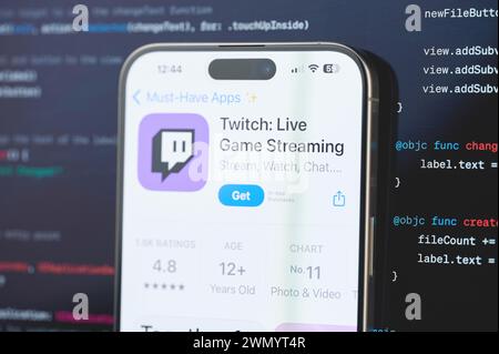 New York, États-Unis - 23 février 2024 : Twitch sur l'écran de l'iphone en arrière-plan de programmation de code flou Banque D'Images