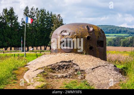 Tourelle blindée montrant des impacts d'obus sur l'ouvrage de la Ferté à Villy, en France, faisant partie de la ligne Maginot, avec un drapeau français flottant au loin. Banque D'Images