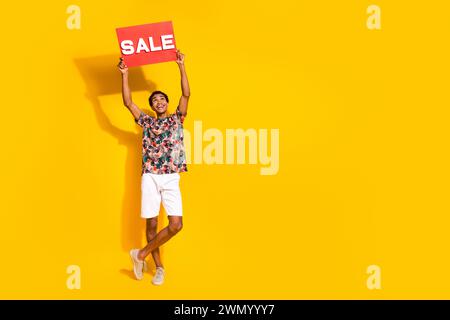 Photo pleine longueur du corps du jeune homme avec la vente de placard rouge regardant au-dessus de la tête pour plus de code qr de réduction isolé sur fond de couleur jaune Banque D'Images