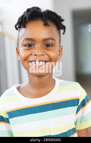 Garçon afro-américain avec un sourire éclatant, portant une chemise rayée Banque D'Images