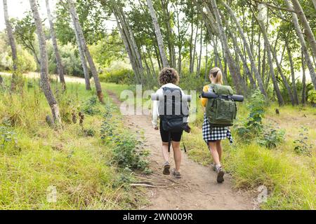 Une jeune femme caucasienne et une jeune femme biraciale font une randonnée dans une forêt luxuriante Banque D'Images