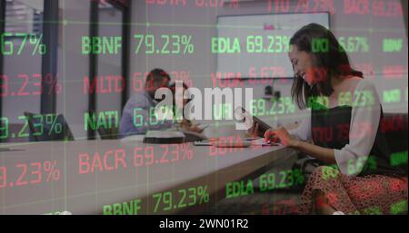 Image des données financières et des graphiques sur la femme biraciale au bureau Banque D'Images